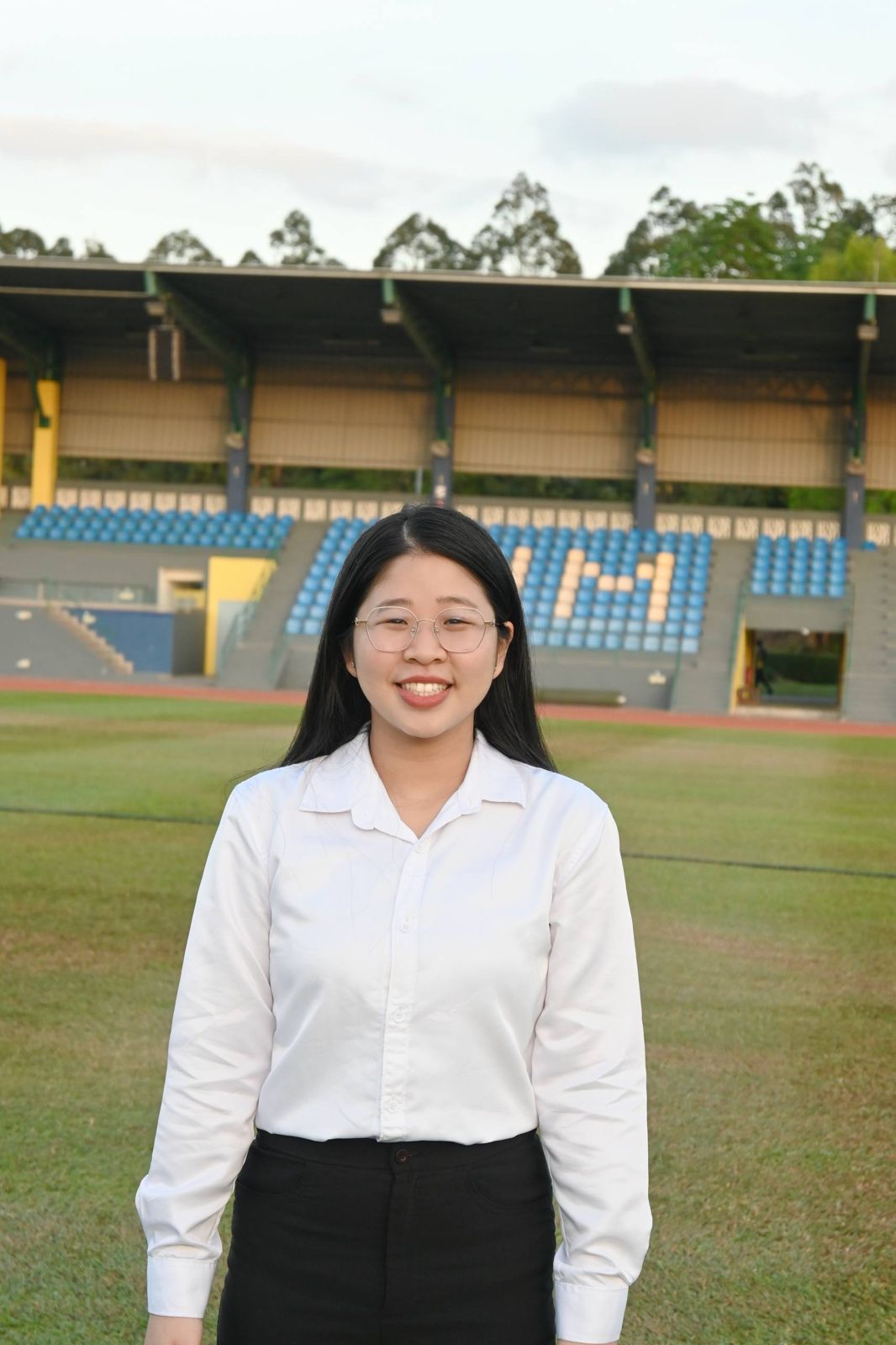 Portrait of Chin Kha Yi in a white shirt standing on a stadium field